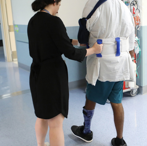 Female nurse helping a young man walk