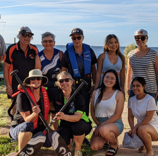 Group of people and students holding dragon boat paddles