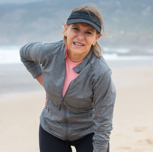 Woman on the beach holding her back