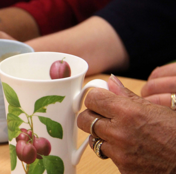 Hands and tea cups of the women’s groups that Anita runs