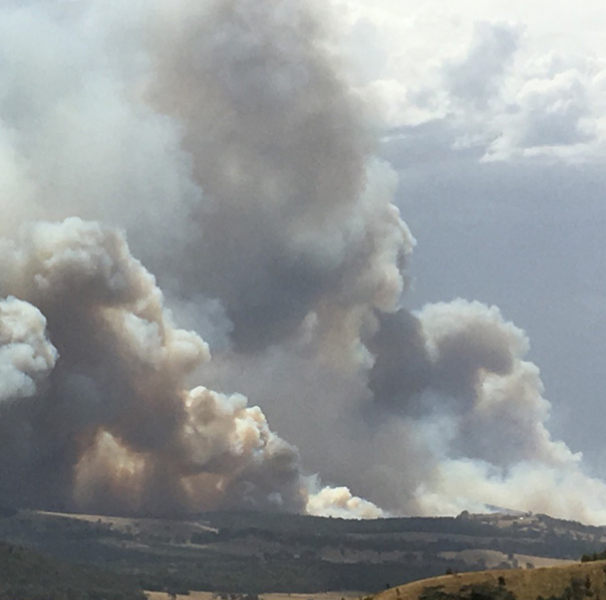 Smoke fills the sky from fires on the hills in the distance