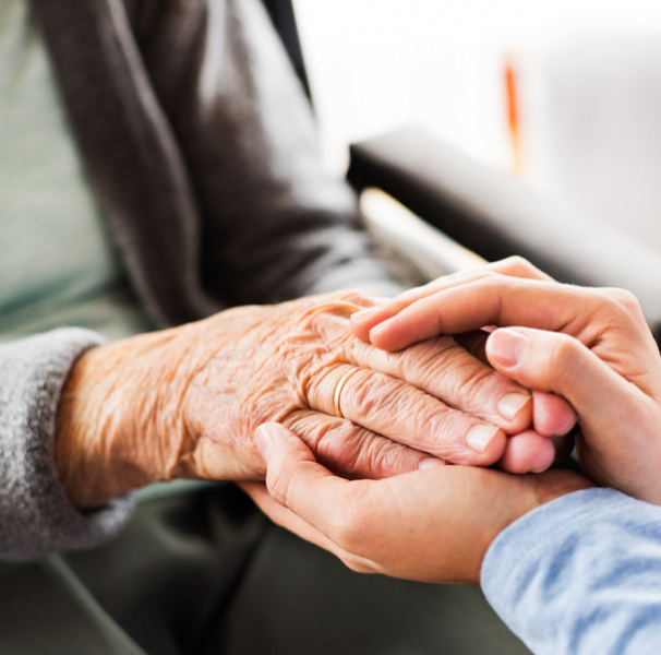 Elderly womans hands being held by younger womans hands
