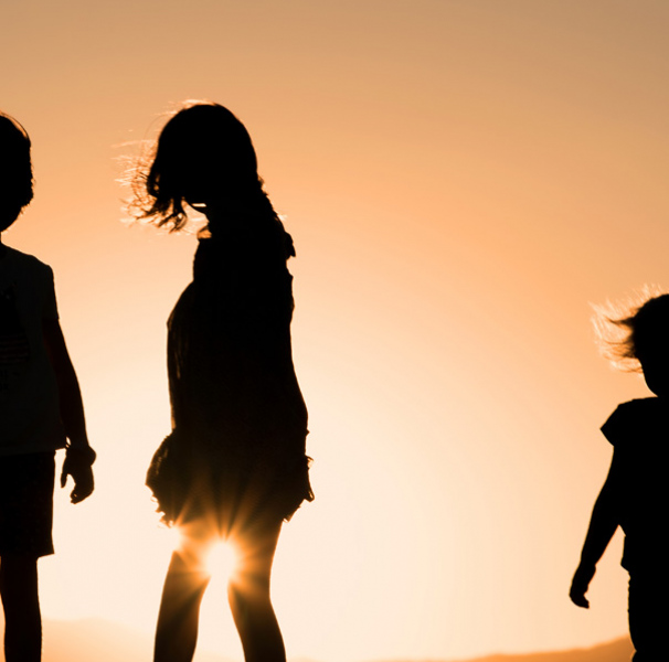 Three children silhouetted at sunset