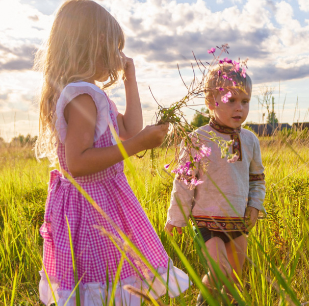 Young girl and boy walking in grassy field