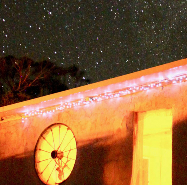 Orange lit roof line of house with starry sky in the background