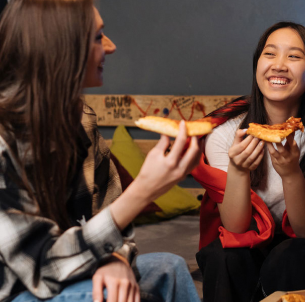 Two teens eating pizza