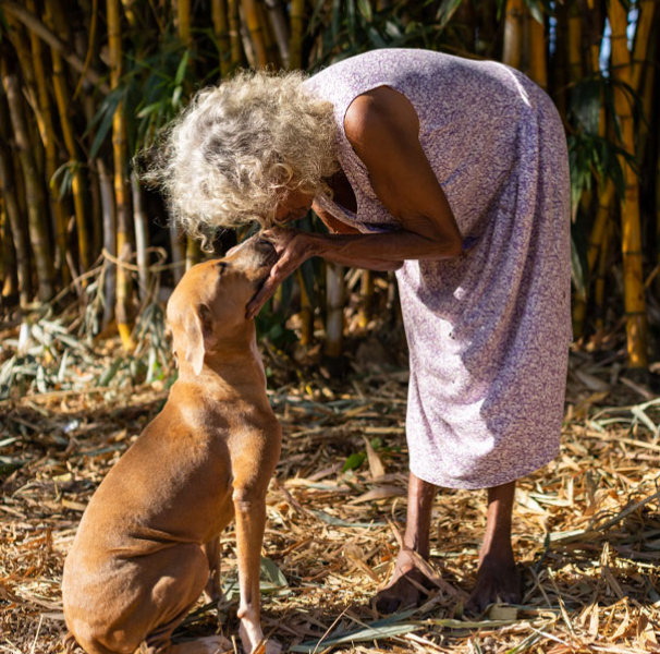 Woman bent over greeting dog. The bond that community members have with their companion animals is hard to put into words,but their wellbeing is inextricably tied to the socioemotional health of remote communities. [Image: AMRRIC]