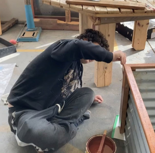 A student lacquers timber on a vegetable planter box. [Image: Thomas Sarah]