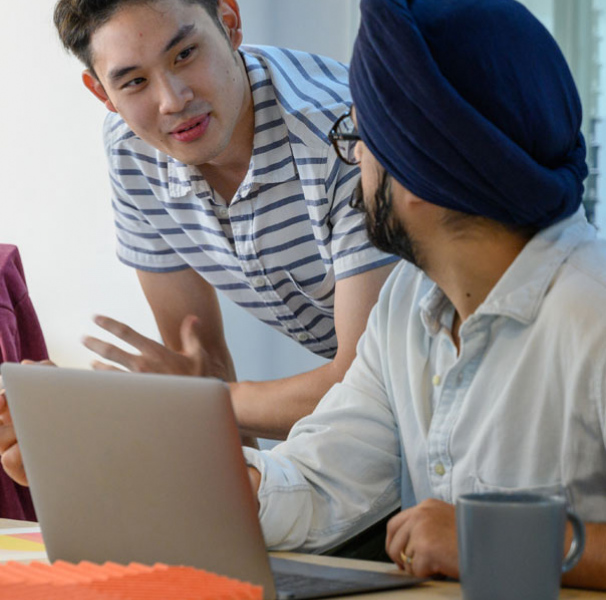 A workplace discussion between two men and a woman in front of laptops