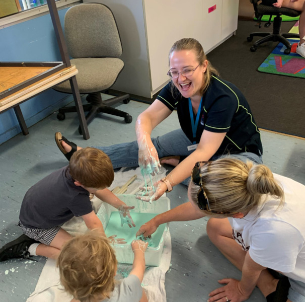 Child and Parent Support worker Kirsten getting messy with some playgroup attendees.