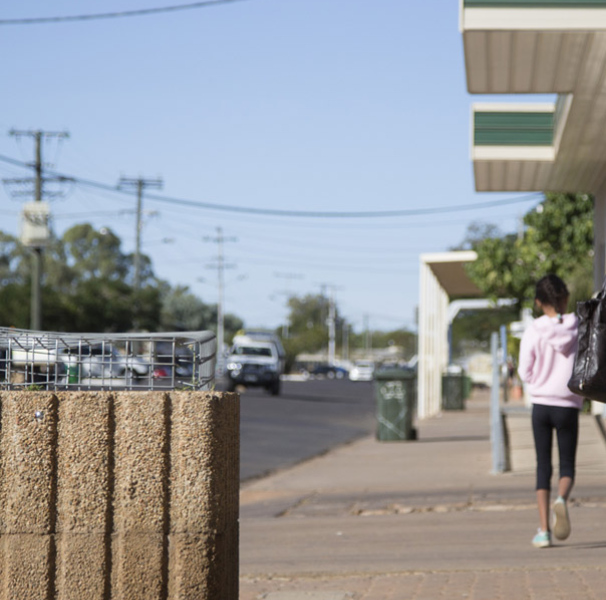 Girl walking on sidewalk of rural street