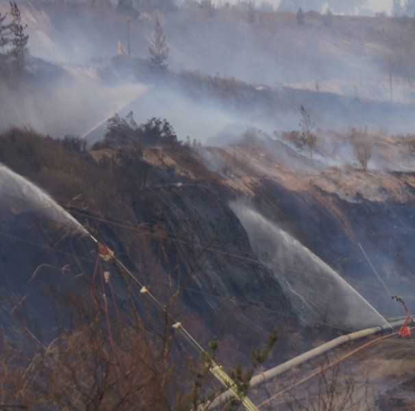 Burnt landscape with fire hoses spraying