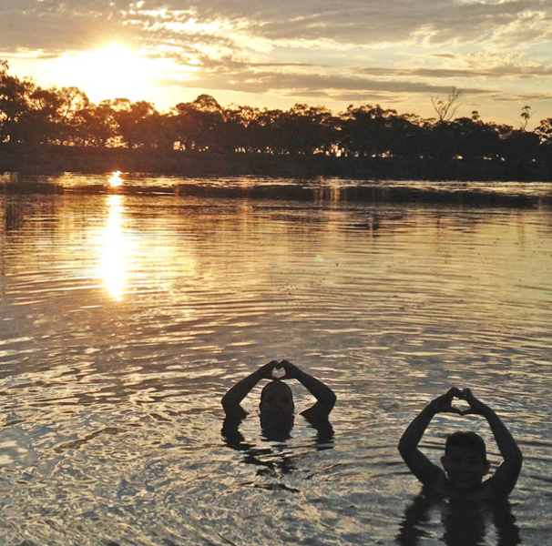Two people swimming at sunset