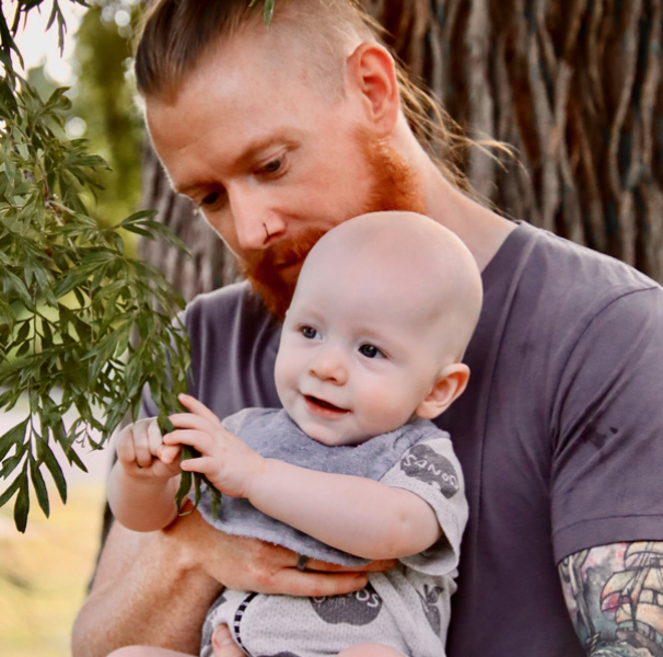 Father and baby in front of tree