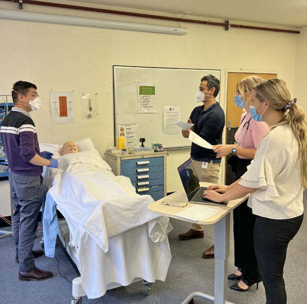 Mock ward round being recorded using GoPro video camera (black device on bedside table)’.