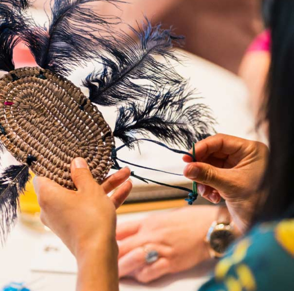 Woman weaving feathers into a craft piece 
