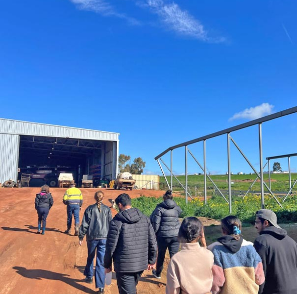 Students walking towards farm shed with industrial sprinkler in the background