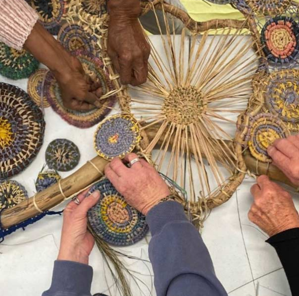 Circle of women's hands holding woven items