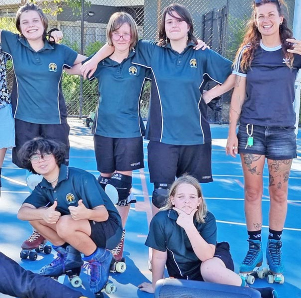School children wearing roller skates on a tennis court