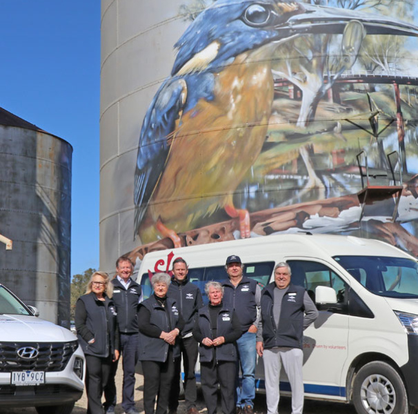 Rochester Community Transport team in front of illustrated grain silos with transport vehicles