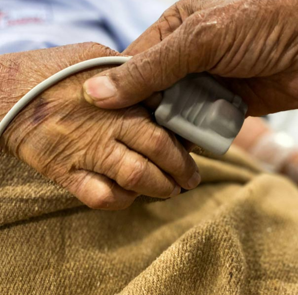 Hand holding patients hand with heart monitor on finger