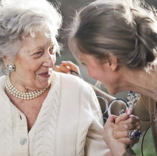 Woman talking to mature woman on park bench