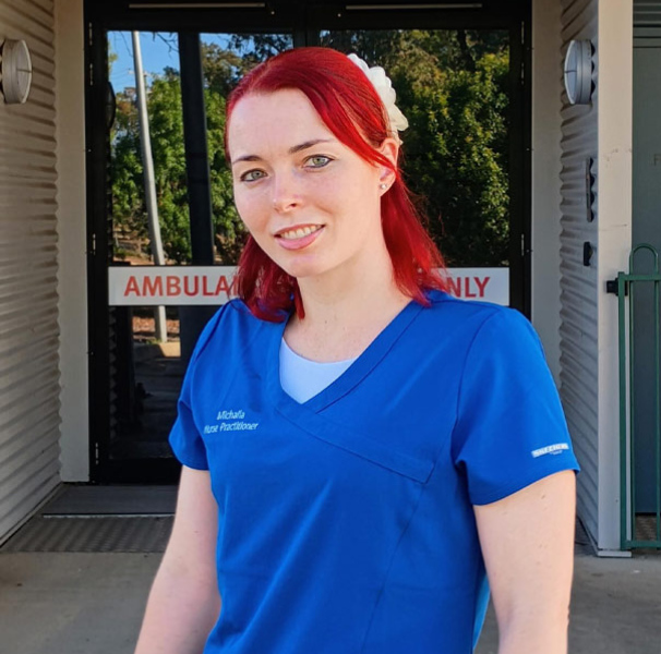 Michaila MacAskill in blue medical clothes in front of medical building