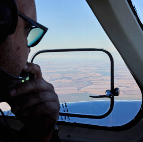 Cockpit view of Roma township with pilot in the foreground using the radio