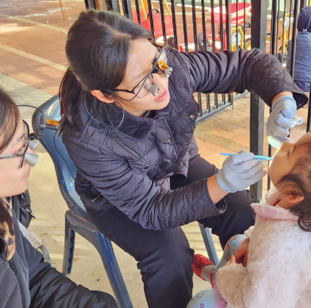 Dentist looking at a young childs mouth in a playground