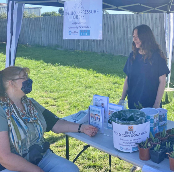 Ashlea Christenson taking a blood pressure check at an outdoor stand/table