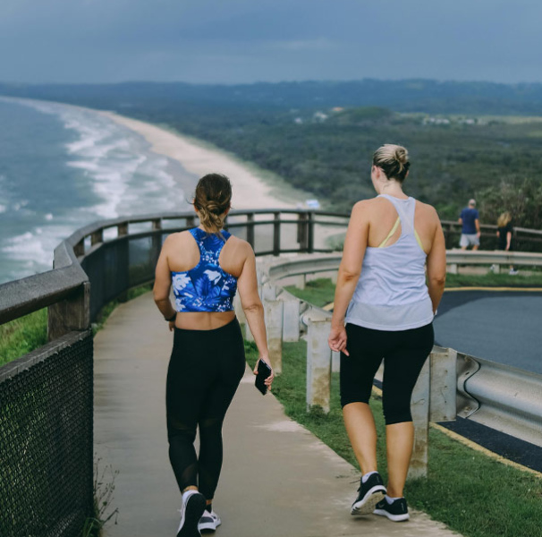 People on a coastal walking pathway overlooking a long beach