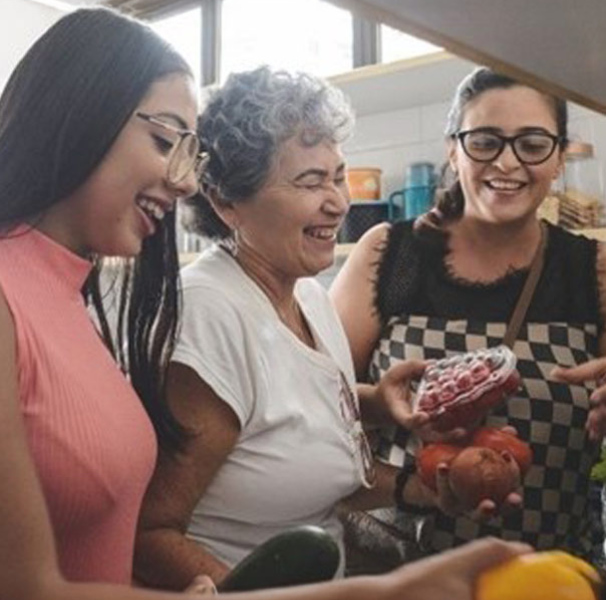 Three women in a kitchen with vegetables