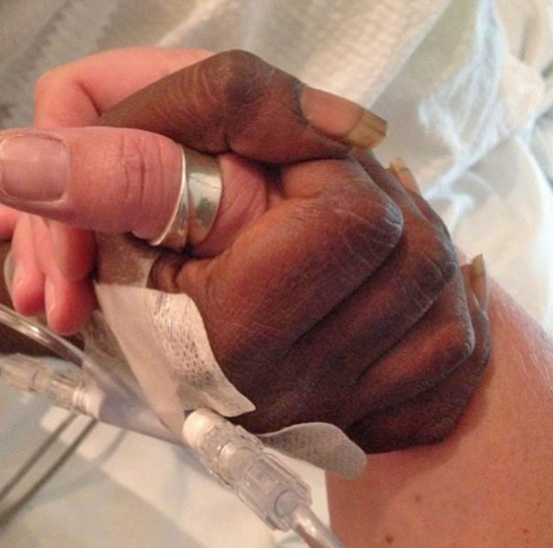 Two hands holding in a medical bed