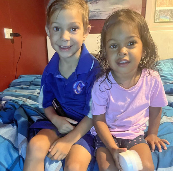 Two preschool age children sitting on a bed