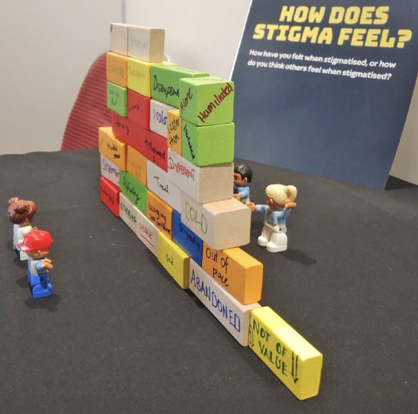 A wall of childrens blocks with emotions written on with some small toy people on either side.